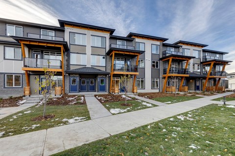 a row of modern apartment buildings with sidewalk and grass